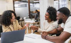 Real estate agent giving keys to happy couple in coworking space
